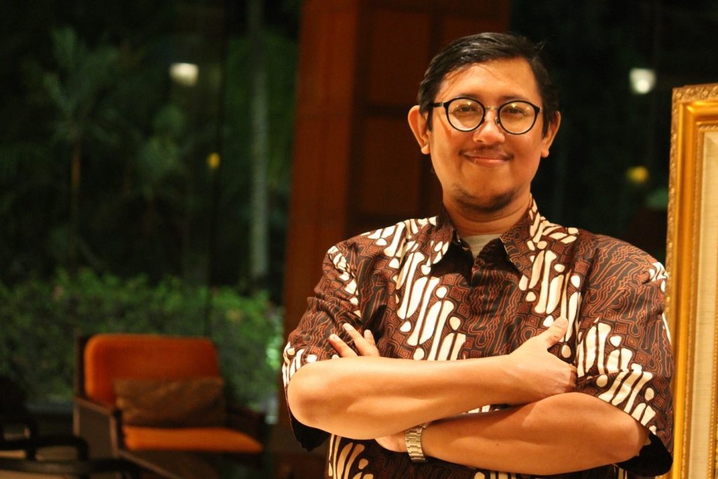 Seorang pria berkacamata berdiri mengenakan pakaian batik menyilangkan tangan, ia adalah Pakar Imunologi dari Departemen Mikrobiologi dan Parasitologi Kedokteran, Fakultas Kedokteran (FK) Universitas Airlangga (UNAIR), dr Agung Dwi Wahyu Widodo dr MSi