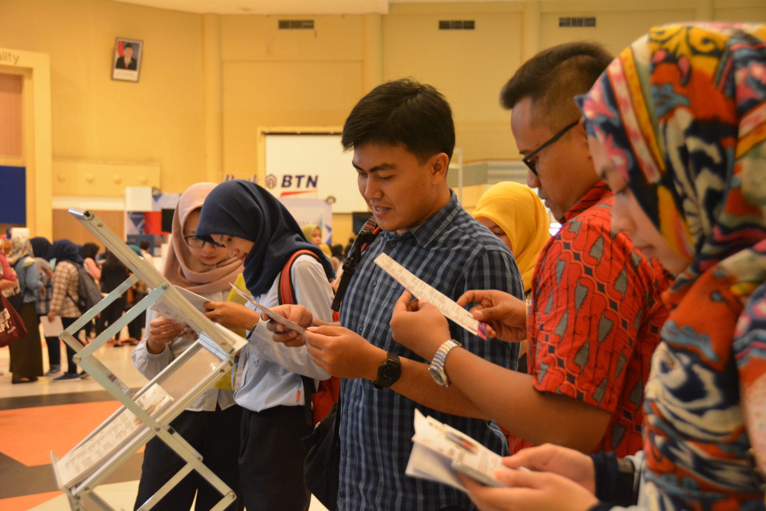 SEJUMLAH peserta membaca syarat berkarir di salah satu perusahaan perbankan peserta job fair dalam Airlangga Career Fair (ACF) di Airlangga Convention Center (ACC) pada Selasa (3/7). (Foto: M. Najib Rahman)