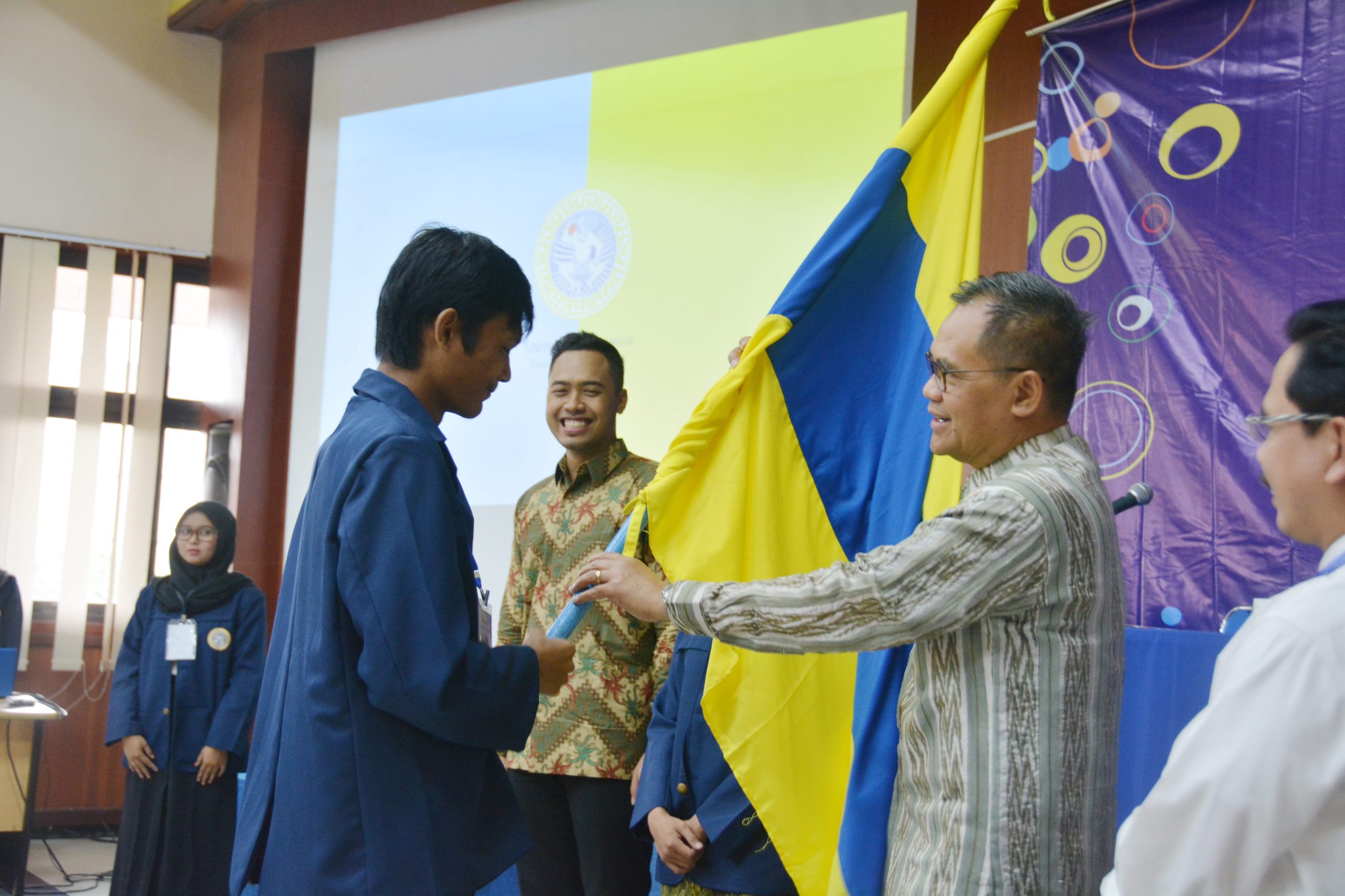 WAKIL Rektor I Prof. Djoko memberikan bendera sebagai penanda keberangkatan tim Bidikmisi Goes to School 2018. (Foto: M. Najib Rahman)