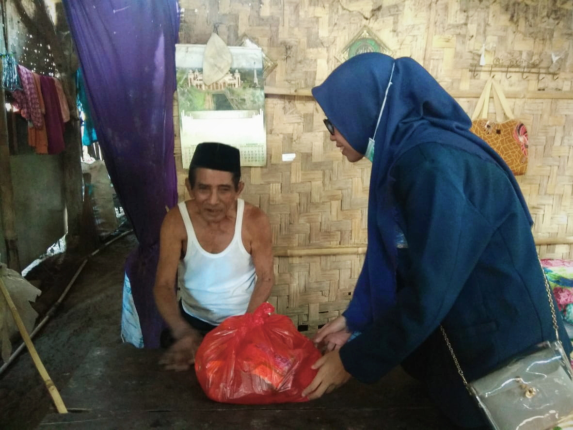 PEDULI: Salah satu mahasiswa PSDKU Banyuwangi yang memberikan sembako dari hasil UNAIR Berbagai kepada salah satu warga desa mitra. (Foto: Istimewa)