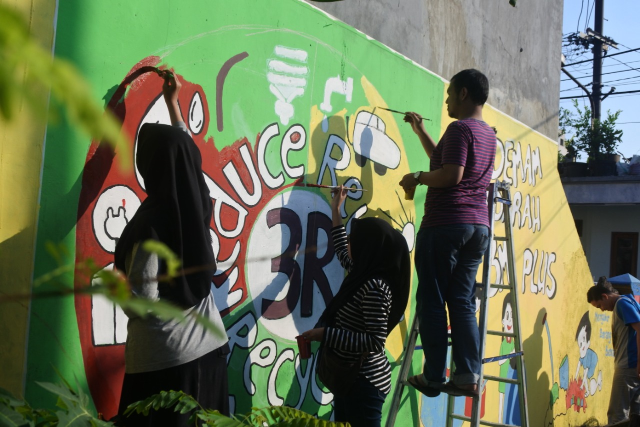 Beberapa warga berpartisipasi dalam kerja bakti kreatif melalui pengecatan di salah satu sudut kampung sekaligus melakukan promosi kesehatan melalui mural yang mereka buat. (Foto: Hilfia Alifa Nurly)