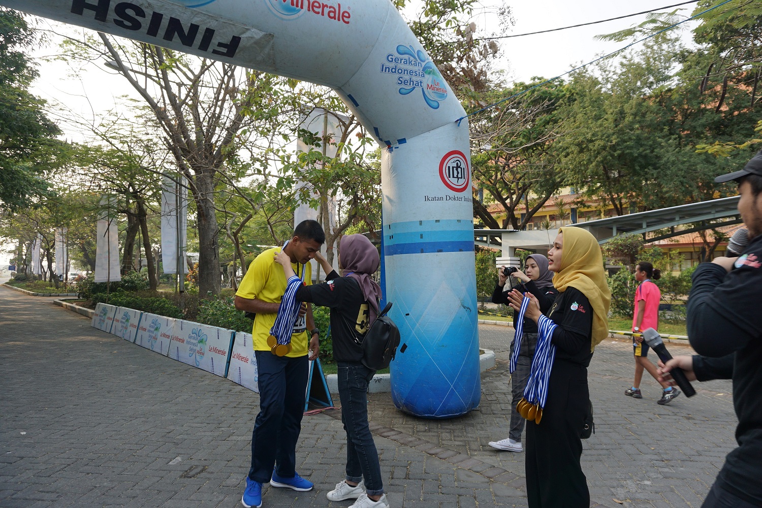 PESERTA yang sudah sampai di garis finish akan diberikan medali oleh panitia pada Minggu (22/9/2019) di sekitar ACC Kampus C UNAIR. (Foto: Istimewa)