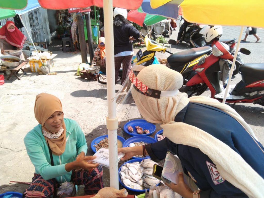 SALAH seorang mahasiswa membagikan masker kepada pedagang pada Selasa (10/11/2020) di Kawasan Surabaya Utara. (Foto: Istimewa)