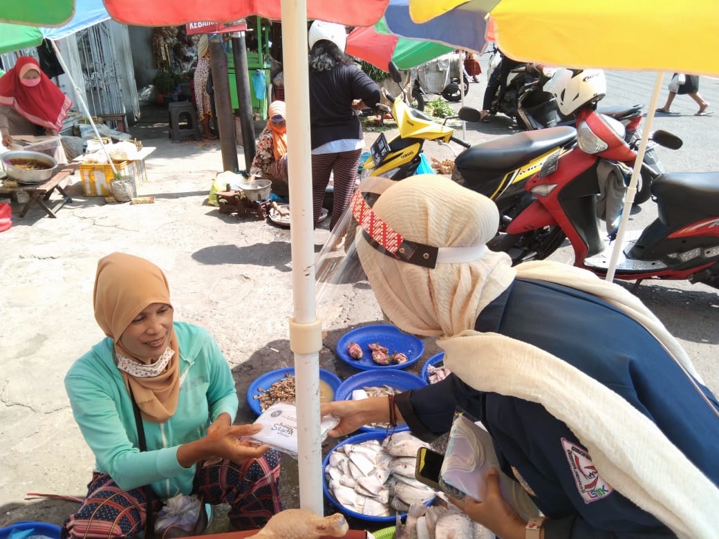 SALAH seorang mahasiswa membagikan masker kepada pedagang pada Selasa (10/11/2020) di Kawasan Surabaya Utara. (Foto: Istimewa)