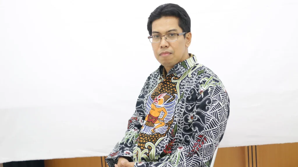 Seorang pria mengenakan kemeja tradisional Indonesia dan kacamata, Prof Dr Sarkawi B Husein.