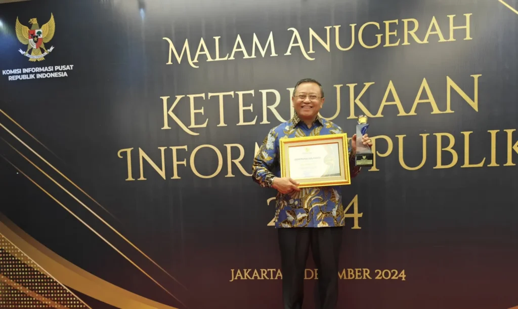 Dr. Koko Srimulyo proudly displays an award during the 2024 Public Information Openness Awards