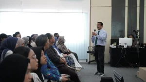 Seorang pria memberikan presentasi kepada sekelompok orang dalam seminar kesehatan FIKKIA