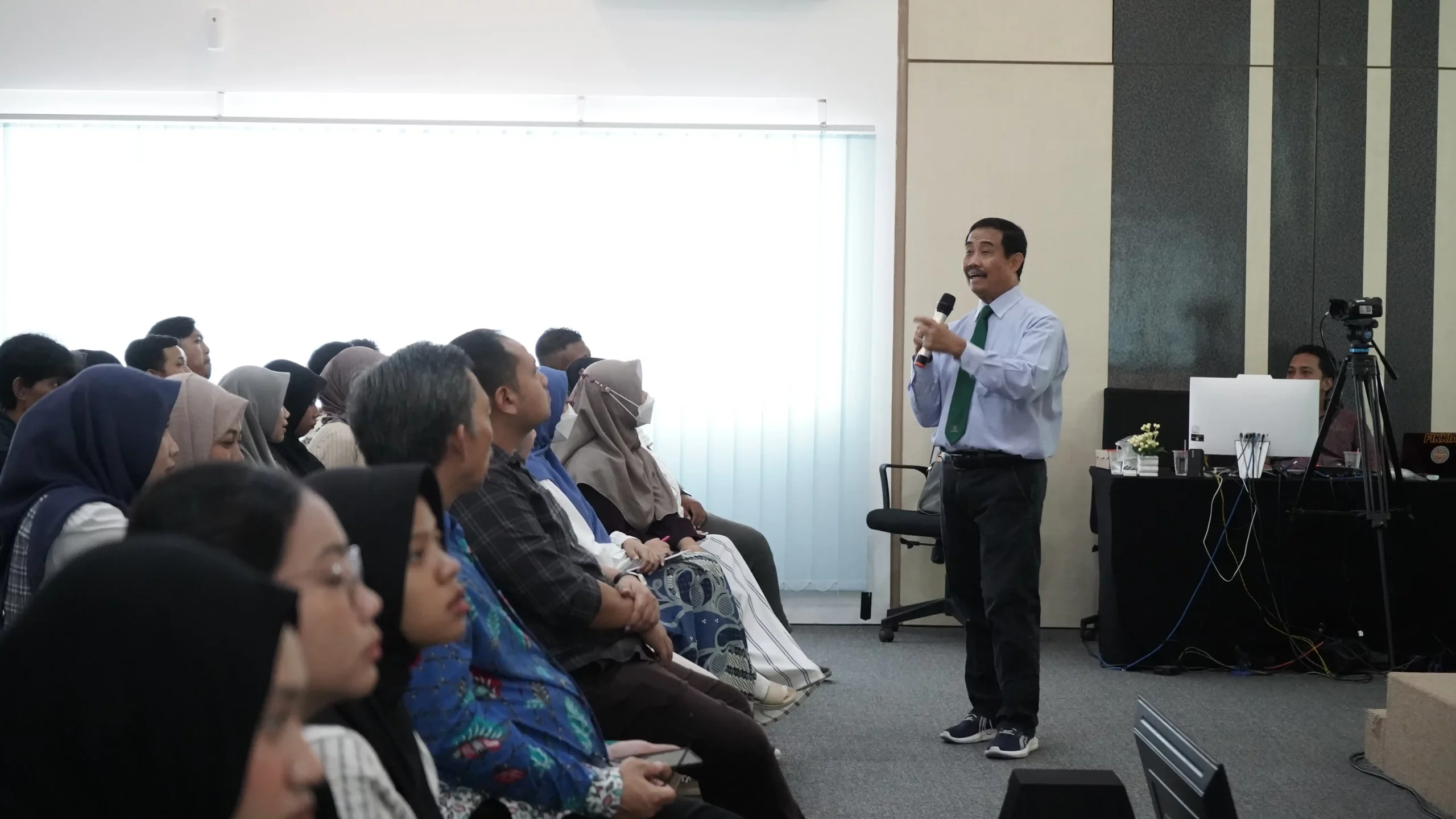 Seorang pria memberikan presentasi kepada sekelompok orang dalam seminar kesehatan FIKKIA