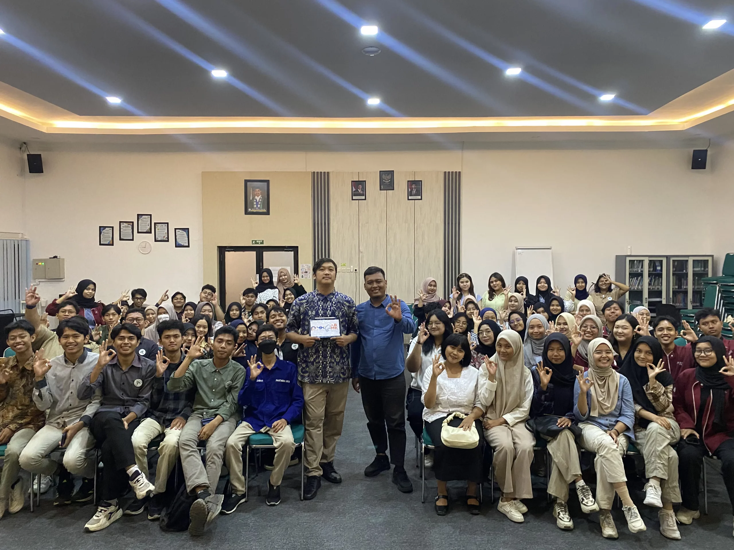 Sekelompok orang berpose untuk foto di ruangan, dalam acara sosialisasi Kompetisi PUSPRESNAS oleh Garuda Sakti FIKKIA