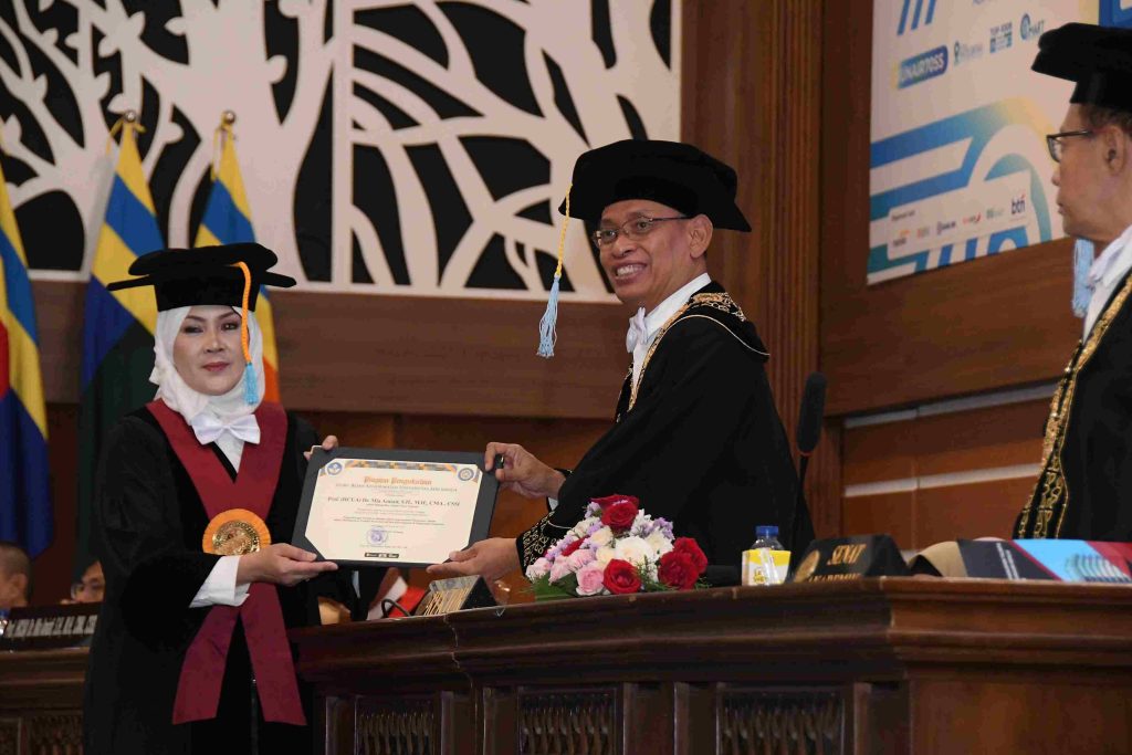 Pria dalam toga wisuda memberikan sertifikat kepada wanita, menandakan pencapaian akademis yang dirayakan.