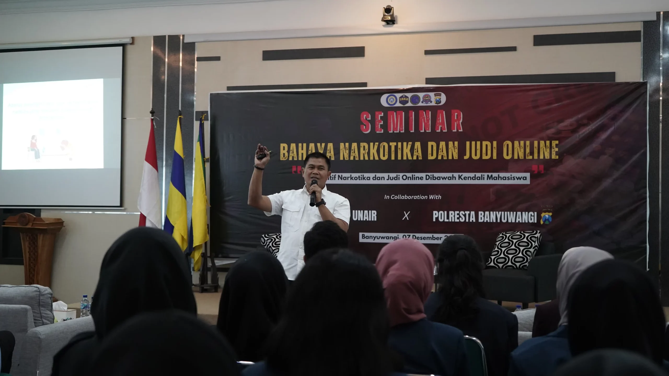 Seorang pria memberikan presentasi bahaya judi online dan narkoba di depan sekelompok orang yang memperhatikan dengan seksama