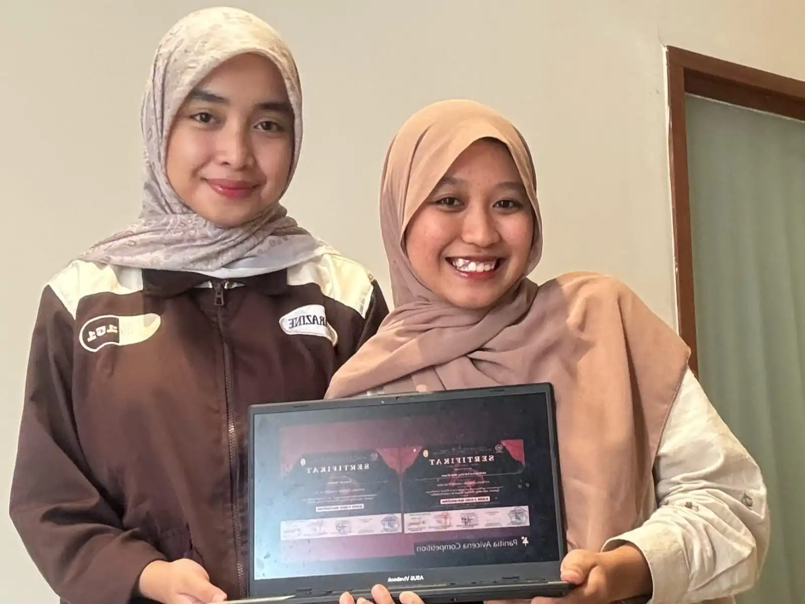 Mahasiswa FF UNAIR, Mifthaku Rahma Wardhani dan Zavirah Silalahi menunjukkan E-Sertifikat juara 3 dalam ajang National Avvicena Competition 2025. (Foto: Istimewa)
