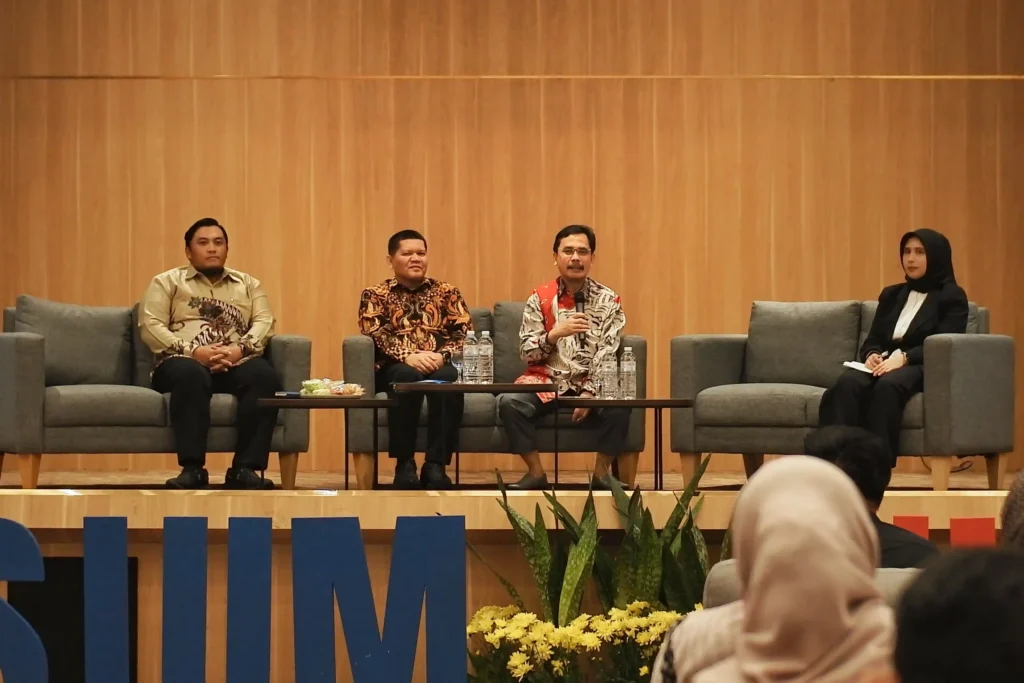 Tiga orang laki-laki dan satu orang perempuan duduk di hadapan para audiens. Ketiga laki-laki merupakan pemateri, sementara satu perempuan adalah moderator.