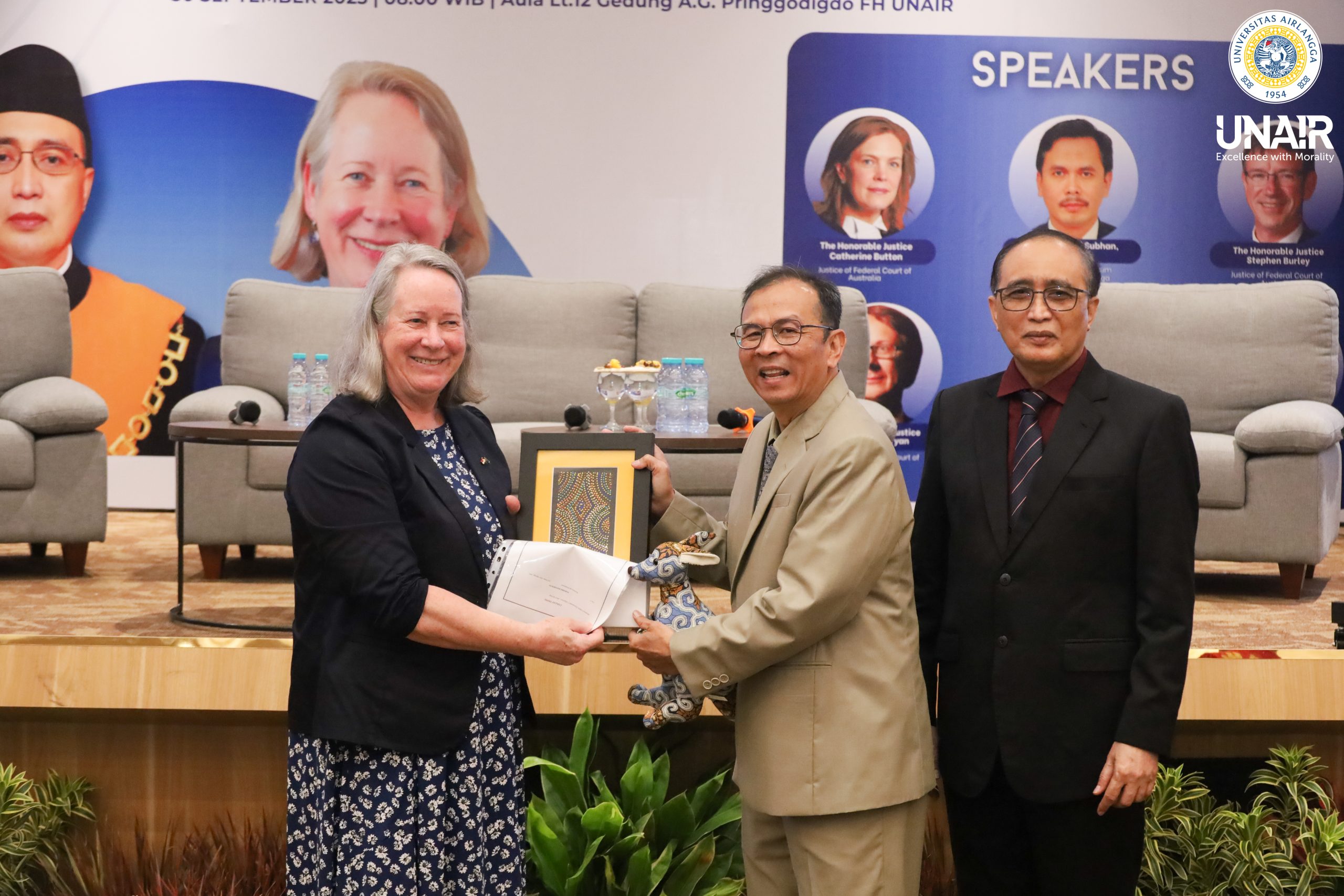 Prof Dr Muhammad Madyan SE MSi MFin, Prof (HCUA) Dr Sunarto SH MH, dan Debra Mortimer dari Federal Court of Australia pada saat sesi penyerahan cinderamata, selasa (30/9/2025). (Foto: Humas UNAIR)