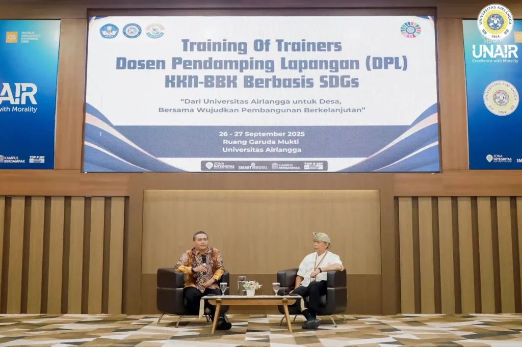 Dua orang lelaki duduk di kursi dengan background bertuliskan Training of Trainers (ToT) Dosen Pendamping Lapangan (DPL) Belajar Bersama Komunitas (BBK)