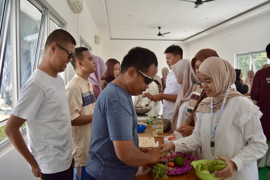 Universitas Airlangga students share a joyful moment with participants with disabilities during a cooking competition session. (Photo: By courtesy)