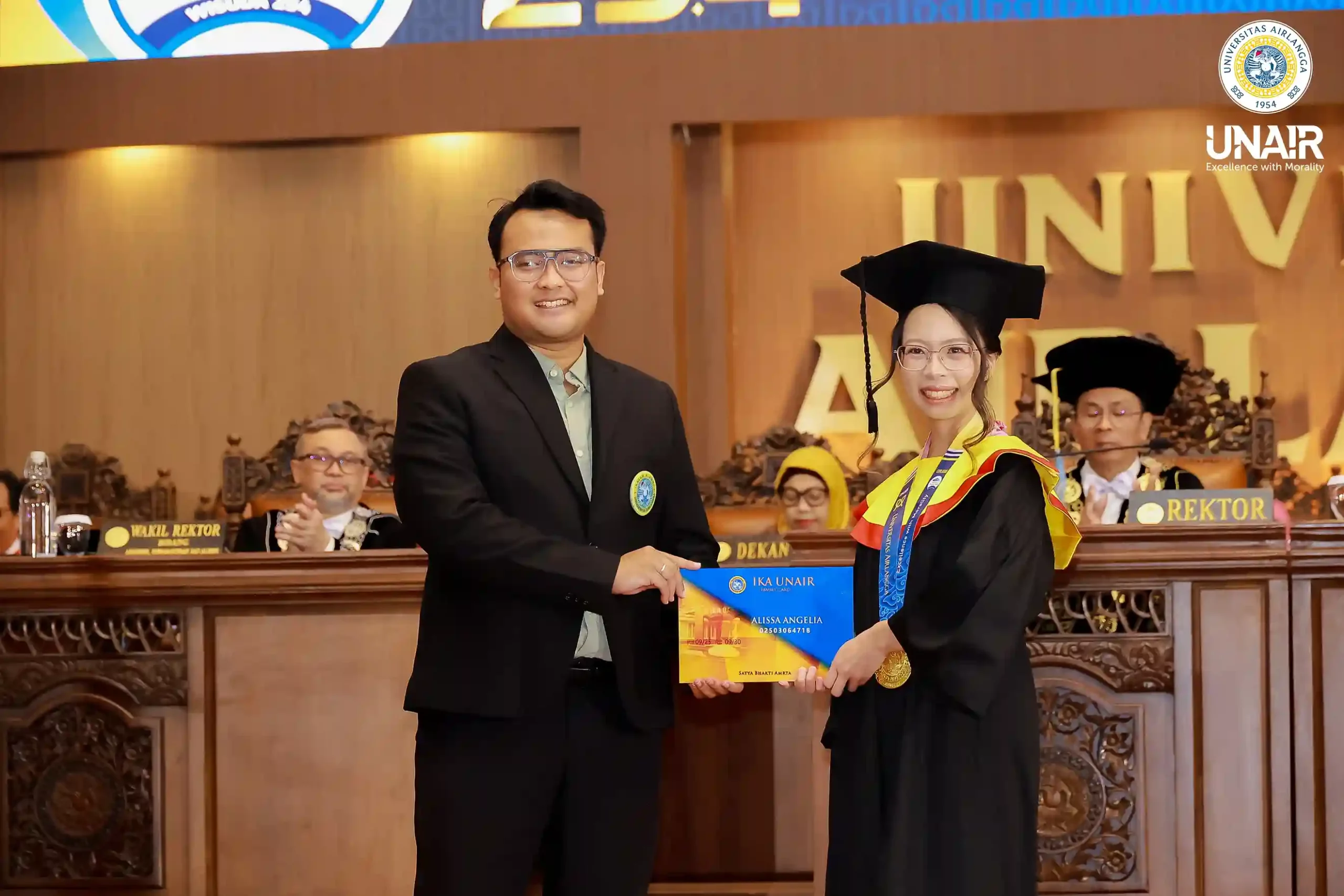 Perwakilan alumni, Fakhri Firdaus (kiri) menyerahkan kartu IKA UNAIR secara simbolis kepada perwakilan wisudawan Alissa Angelia