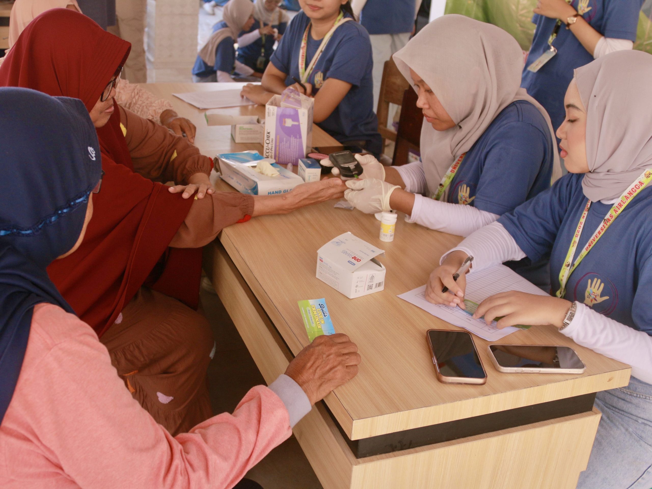 Mahasiswa FKM UNAIR bersama mahasiswa internasional melakukan pemeriksaan kesehatan berupa pengecekan tekanan darah dan gula darah kepada warga Desa Banjardowo. (Foto: Istimewa)