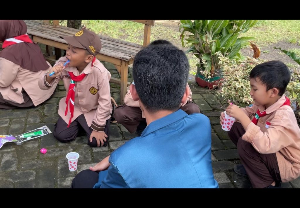 Mahasiswa BBK 7 Universitas Airlangga mendampingi siswa SDN 1 Sukosari mempraktikkan cara menyikat gigi yang benar dalam program edukasi kesehatan BERSERI di lingkungan SDN 1 Sukosari, Kecamatan Trawas, Kabupaten Mojokerto, pada Sabtu (17/01/2026). (Foto: Vientessa Calistania Mahardika)