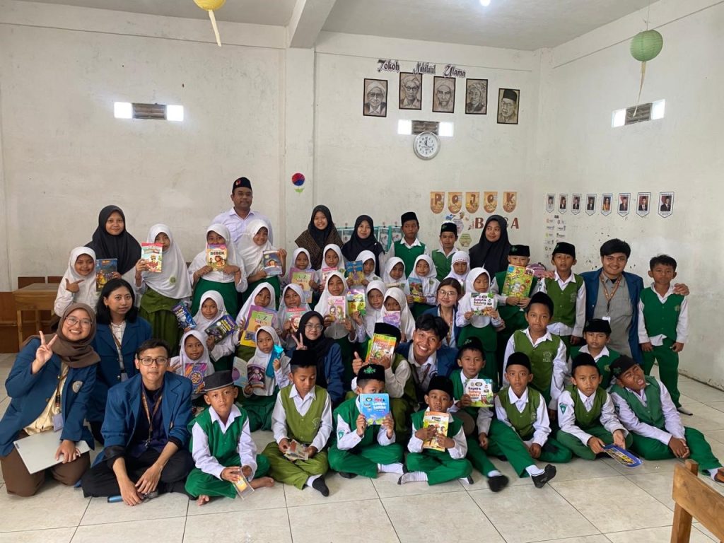 Tim Mahasiswa BBK 7 UNAIR memberikan kenang-kenangan erupa buku kepada MI NU Jatidrojog