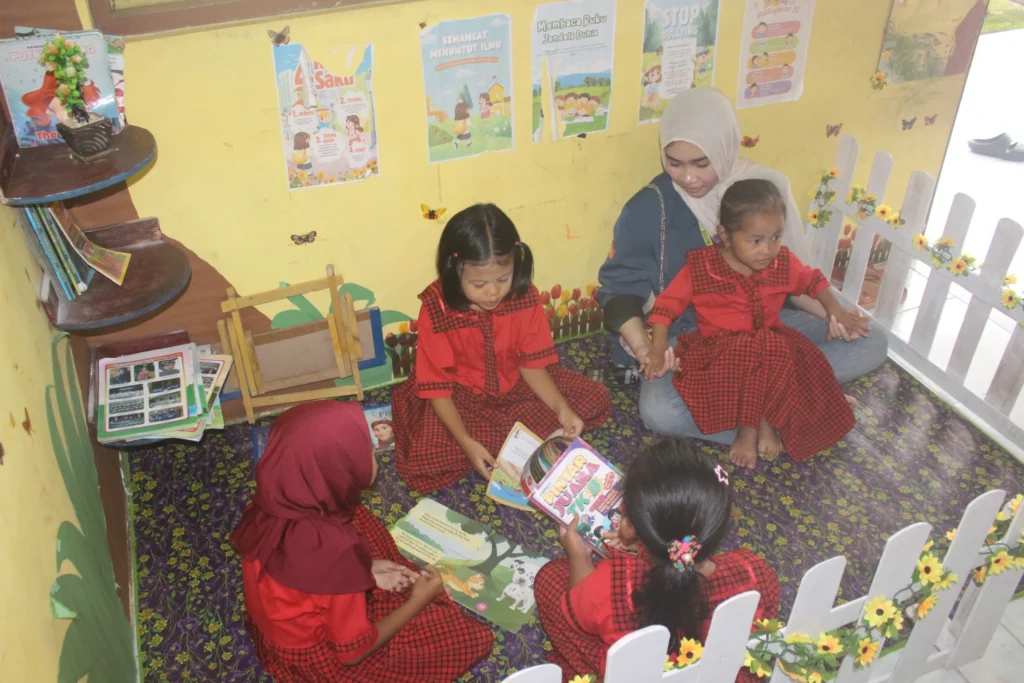 Mahasiswa KKN BBK 7 Mendampingi anak-anak TK di Desa Karangcangkring saat memanfaatkan Pojok Baca sebagai sarana literasi dan pembelajaran di dalam kelas.