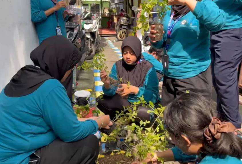 Mahasiswa BBK 7 Universitas Airlangga saat sedang menanam tanaman gantung dari botol plastik daur ulang dalam Program RESIKAN di Kelurahan Kroman, Minggu (25/1/2026).