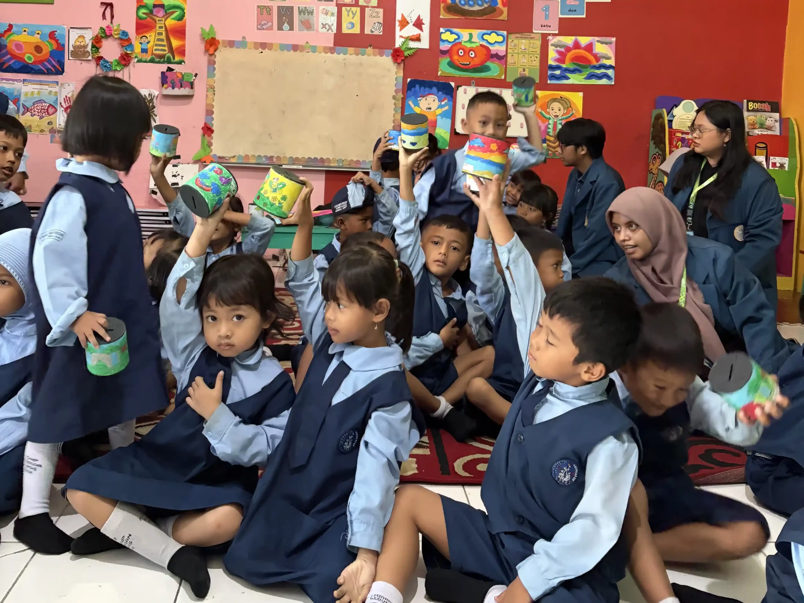 Murid TK Dharma Wanita Persatuan Desa Kembangan menunjukkan celengan hasil kegiatan Cilik Cerdas Finansial yang dilaksanakan oleh Mahasiswa BBK Gresik, Senin (12/1/2026).