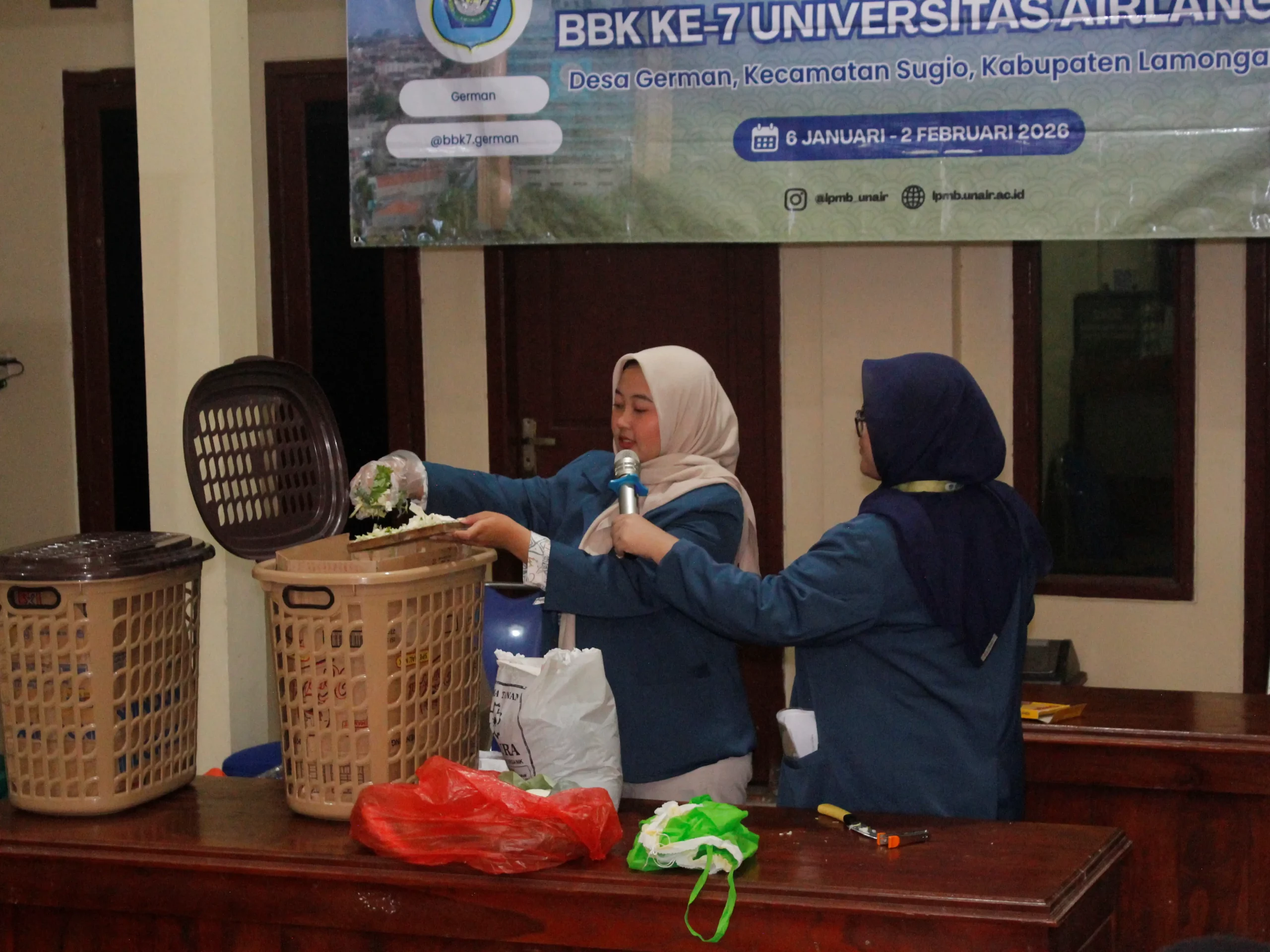 Mahasiswa KKN BBK 7 Universitas Airlangga melakukan demonstrasi pembuatan kompos organik dengan metode Takakura dan disaksikan secara langsung oleh warga dalam program TAKOSA di Balai Desa German, Kecamatan Sugio, Kabupaten Lamongan, Senin (26/1/2026). (Foto: Dok. Pribadi)