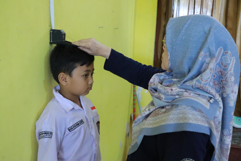 Tahap pengukuran tinggi badan dalam proses skrining status gizi pada SDN Mayangrejo, Selasa (6/7/2026). (Foto: PHMP UNAIR)