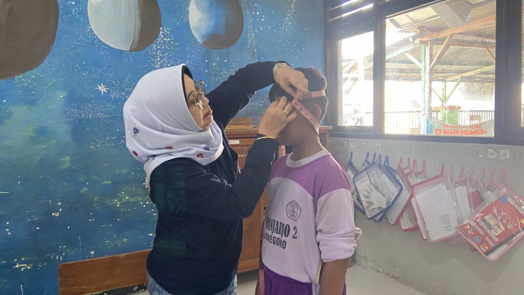 Dekan FKH UNAIR, Prof Dr Lilik Maslachah drh MKes saat sesi pengukuran lingkar kepala pada siswa di SDN Banjarjo II Bojonegoro, Senin (6/7/2026). (Foto: Erika Eight Novanty)