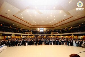 Sesi foto bersama jajaran pimpinan UNAIR bersama para mahasiswa BBK ke-8 pada Upacara Pelepasan Mahasiswa Belajar Bersama Komunitas (BBK) ke-8 Universitas Airlangga (UNAIR) di Airlangga Convention Center (ACC), Minggu (12/7/2026). (Foto: PHMP UNAIR)