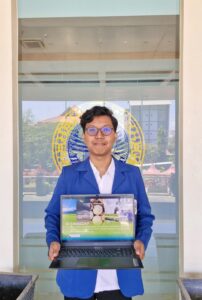 Mahasiswa S1 Kimia FST UNAIR Abraham Alexs Tanu Wijaya menunjukkan karya esainya berjudul “SI-TANGGAP” yang meraih Juara I FISION 2026. (Foto: Dokumentasi Pribadi)