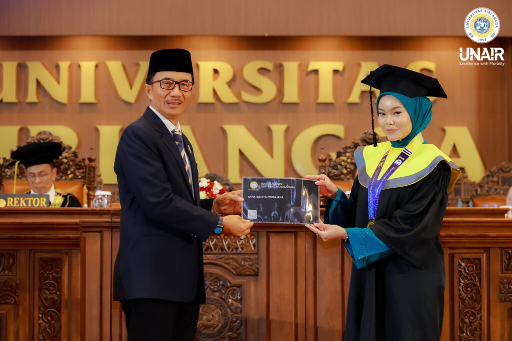 FOTO PP IKA UNAIR, Dr M Syaiful Aris SH MH LLM saat memberikan kartu IKA kepada salah satu wisudawan terbaik Afra Bahita Fridajaya. (Foto: Humas UNAIR)