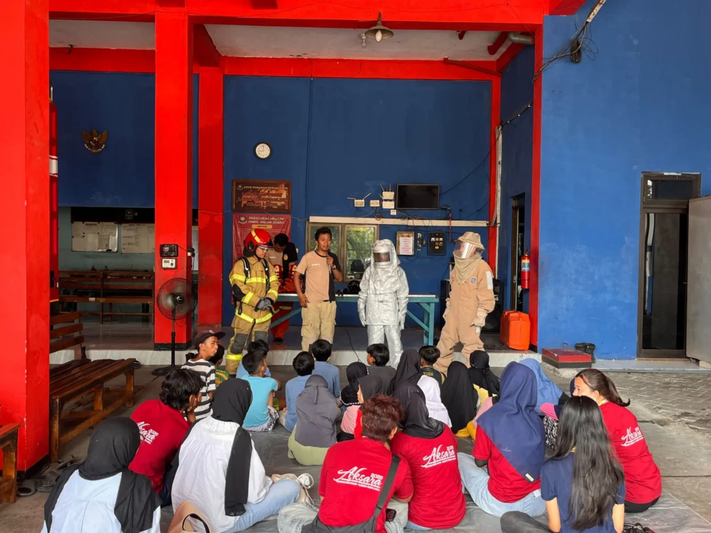 Anak-anak Kampung Sukolilo Baru mengikuti penyuluhan mengenai mitigasi kebakaran dalam kunjungan edukatif AKSARA 2026 di Dinas Pemadam Kebakaran dan Penyelamatan (DPKP) Rayon 3 Surabaya, Rungkut Industri, Minggu (20/9/2026). (Foto: Tim Media AKSARA 2026)