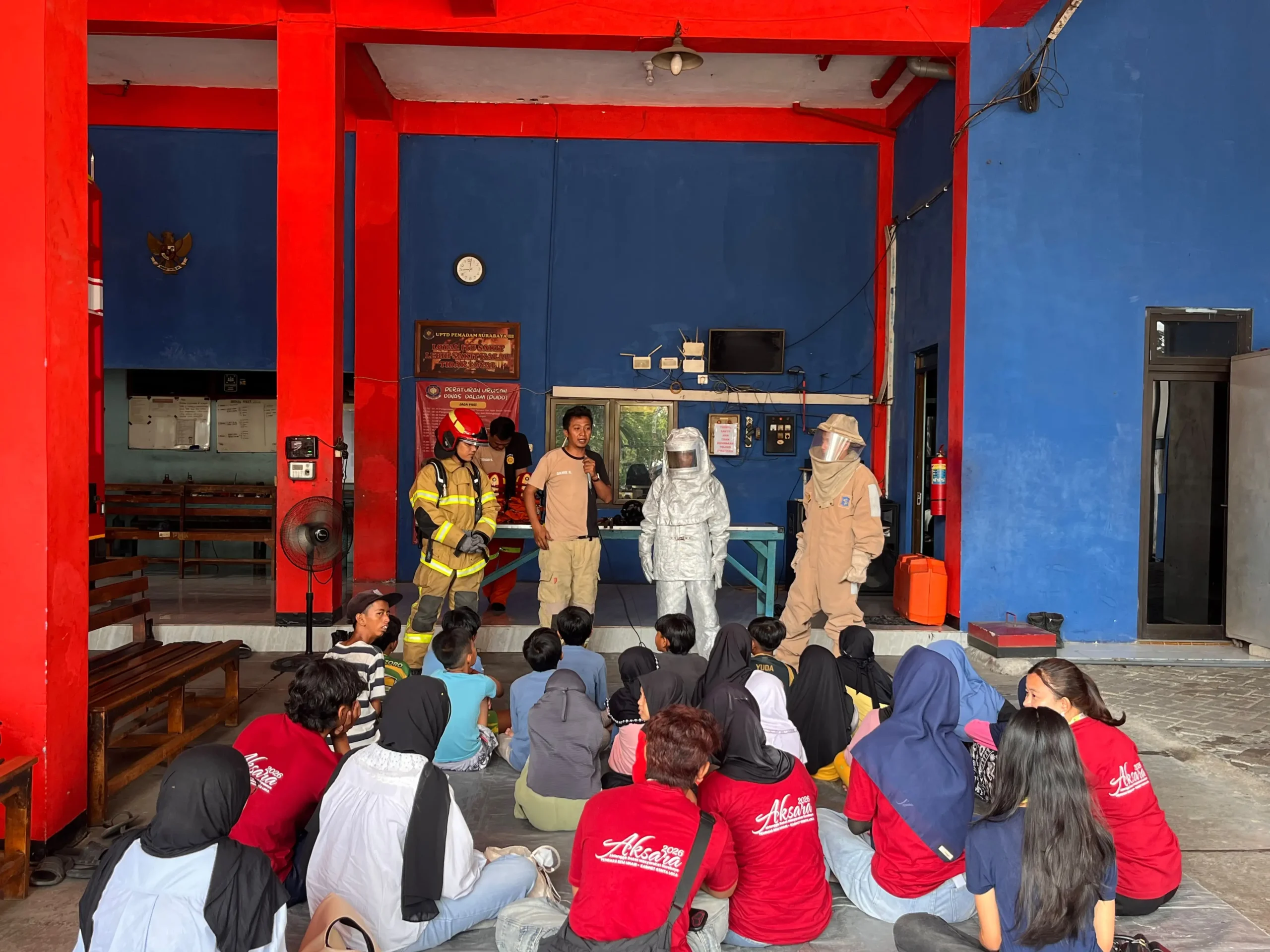 Anak-anak Kampung Sukolilo Baru mengikuti penyuluhan mengenai mitigasi kebakaran dalam kunjungan edukatif AKSARA 2026 di Dinas Pemadam Kebakaran dan Penyelamatan (DPKP) Rayon 3 Surabaya, Rungkut Industri, Minggu (20/9/2026). (Foto: Tim Media AKSARA 2026)