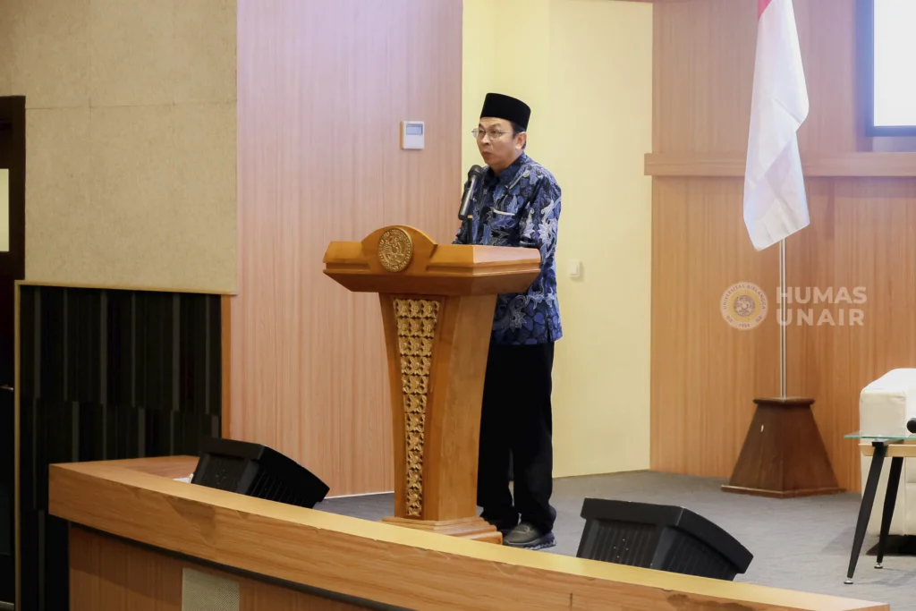Seorang laki-laki mengenakan batik dan berpeci berbicara di podium. Ia adalah rektor UNAIR, Prof Dr Muhammad Madyan SE MSi MFin