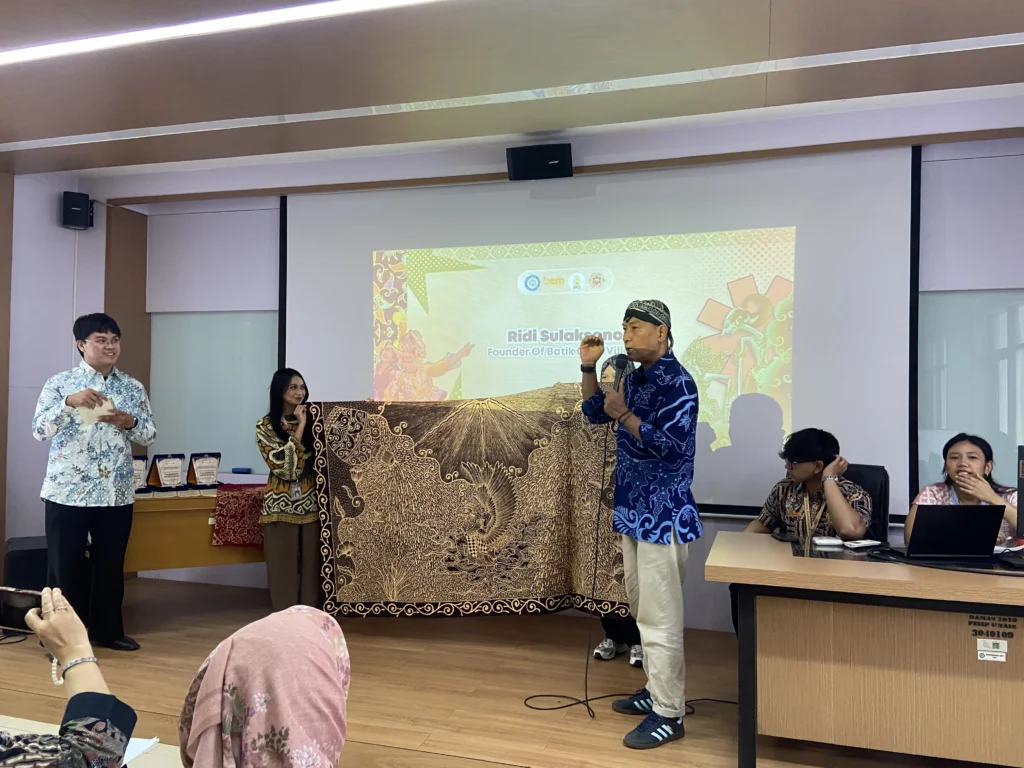 Pendiri Kampung Batik Okra, Ridi Sulaksono, saat menjelaskan filosofi motif "Batik UNAIR" yang dirancang khusus untuk Universitas Airlangga dalam rangkaian sesi materi AICECS 2026, Selasa (20/10/2026). (Foto: Dok. Istimewa)