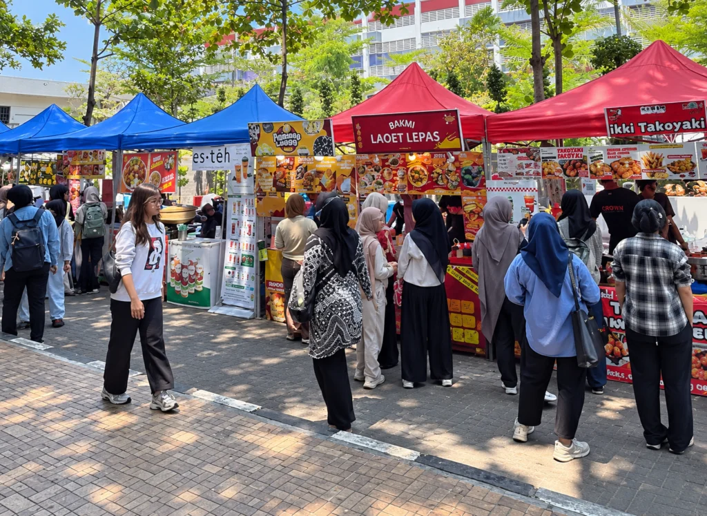 Pengunjung berinteraksi langsung dengan pelaku usaha saat mengunjungi salah satu stan UMKM dalam pergelaran pasar kreatif Pop Up Mart 2026 di area Samping FISIP pada Kamis (15/10/2026). (Foto: Istimewa)