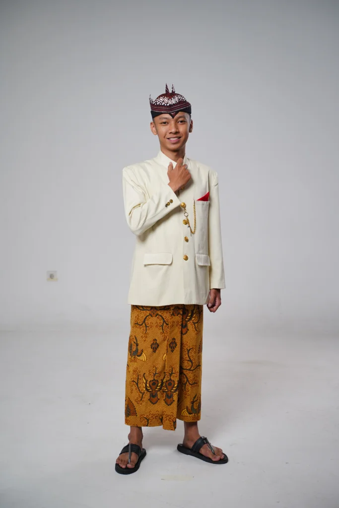 Seorang laki-laki mengenakan pakaian adat jawa, berdiri menghadap kamera. Ia adalah Delvin Erwi Anggara, Finalis Cak Surabaya 2026, Mahasiswa Ilmu Ekonomi Fakultas Ekonomi dan Bisnis (FEB) UNAIR